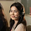 Agente sonriendo con auriculares, atendiendo desde la computadora