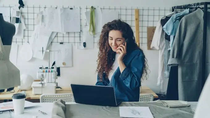 Dueña de taller atendiendo por teléfono mientras trabaja